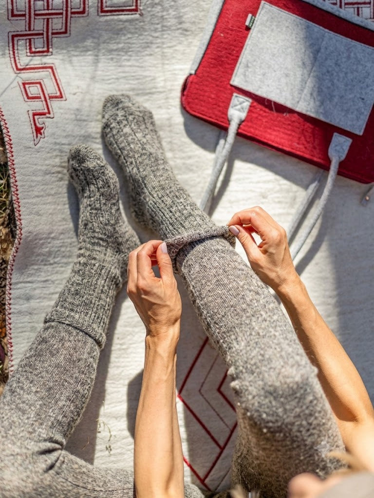 Chaussettes mi-mollet MONLAINE en laine de Mongolie, coloris Gris Steppe, portées en extérieur sur un tapis traditionnel, scène lifestyle.